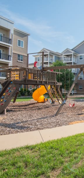 a playground with a swing set in front of an apartment building