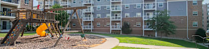 a playground with a swing set in front of an apartment building