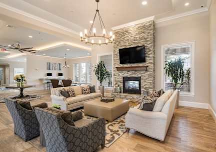 A living room with a stone fireplace and a flat screen TV mounted above it.