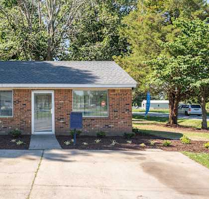 a small brick house with a sidewalk in front of it