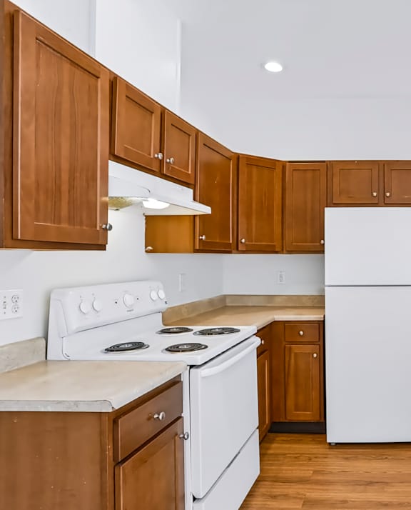 A kitchen with white appliances and wooden cabinets.