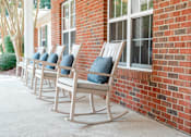 Thumbnail 1 of 5 - a row of rocking chairs outside of a brick building