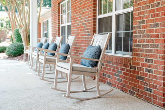 a row of rocking chairs outside of a brick building