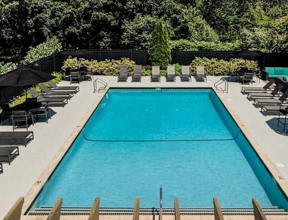 A large outdoor swimming pool surrounded by lounge chairs and umbrellas.