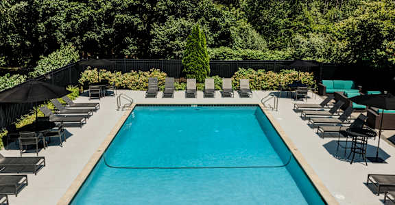 A large outdoor swimming pool surrounded by lounge chairs and umbrellas.