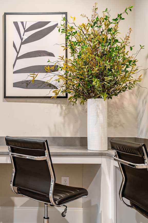 A white desk with a laptop and two chairs.
