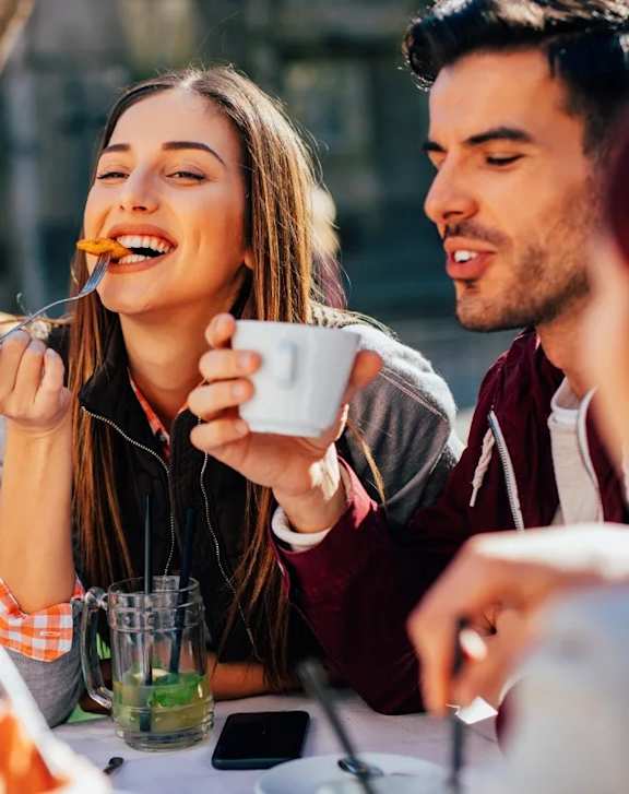 A man and a woman are enjoying a meal together outdoors.
