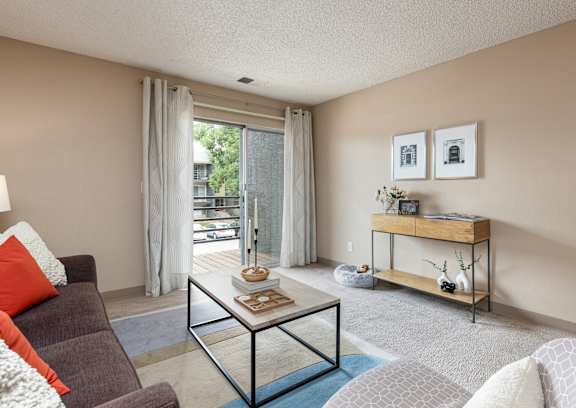 A living room with a glass coffee table and a grey sofa.