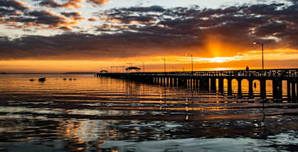a sunset over a pier at the beach