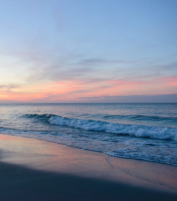 a sunset on the beach with the ocean and waves