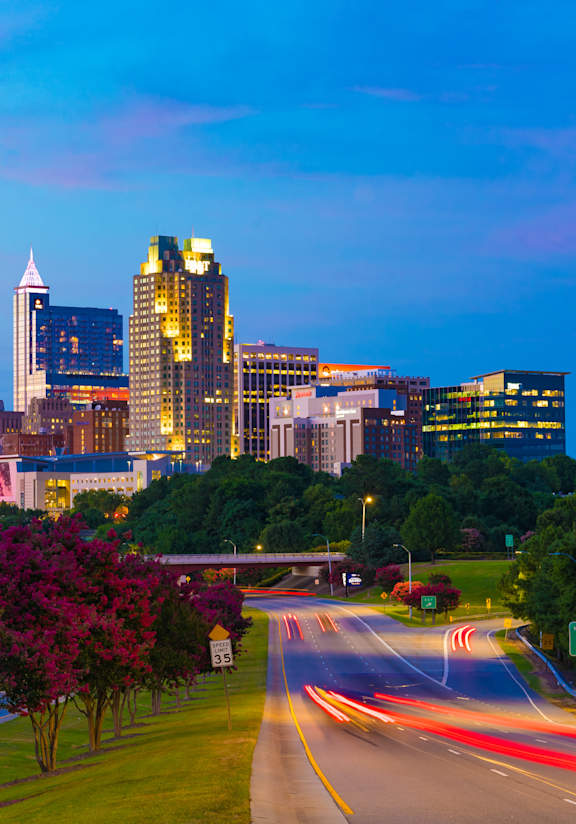 A city skyline at dusk with a long exposure of the street in front.