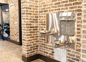 Thumbnail 9 of 9 - A brick wall with a water dispenser attached to it. at District on the Etowah Apartments, Canton Georgia