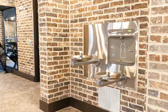 A brick wall with a water dispenser attached to it. at District on the Etowah Apartments, Canton Georgia