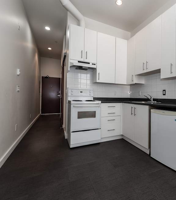 A kitchen with white cabinets and black countertops.