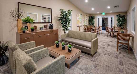 A waiting room with a couch, chairs, and a mirror.