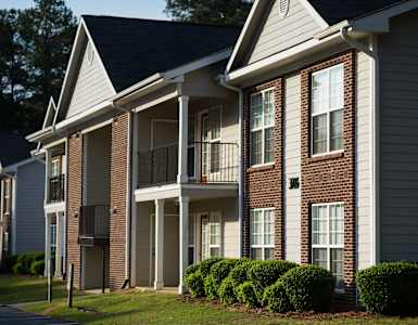 a brick apartment building with a balcony and a yard