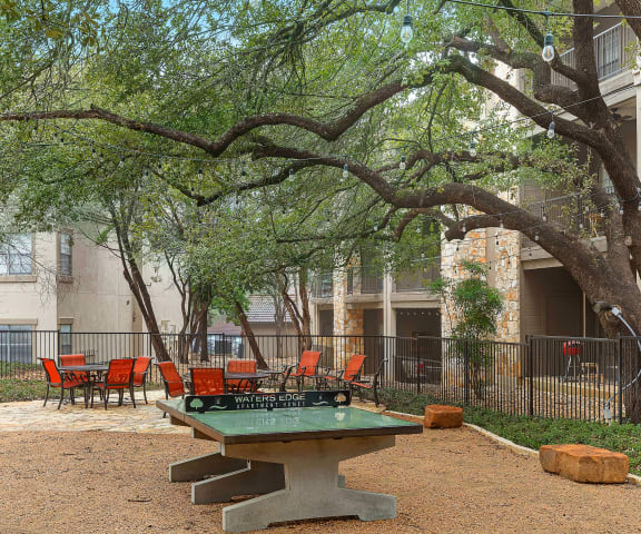 a picnic area with a ping pong table in front of an apartment building