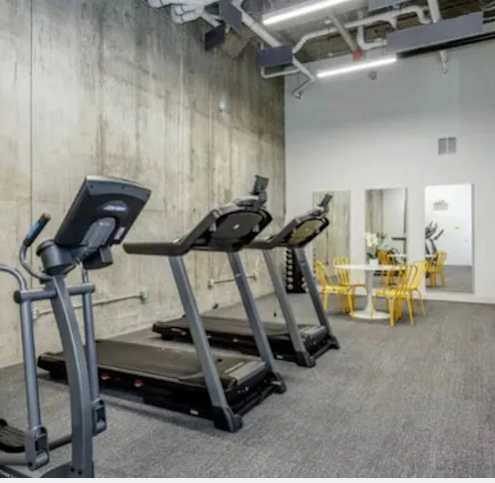 A gym with treadmills and a dining table.