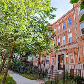 A red brick building with a black iron fence in front.