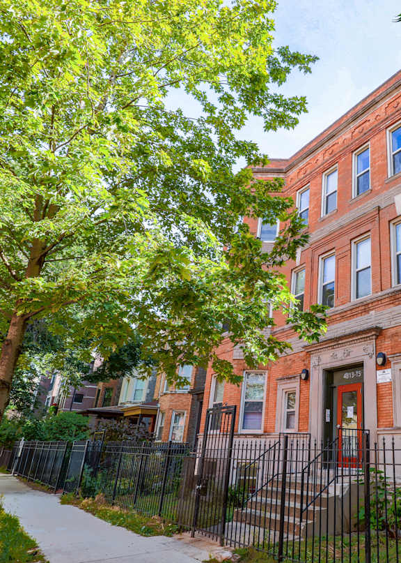 A red brick building with a black iron fence in front.