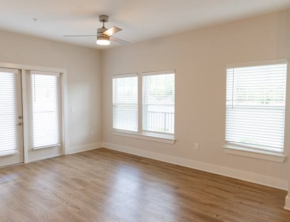 A room with a ceiling fan and three windows.