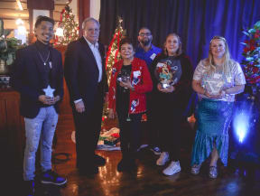 a group of people standing in front of a christmas tree