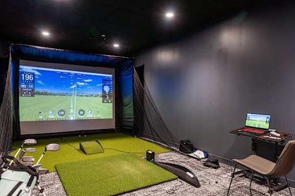 A room with a projector screen and a laptop on a desk.