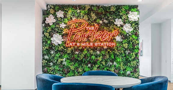 A green wall with flowers and the words "The Parker at Smile Station" written in neon.