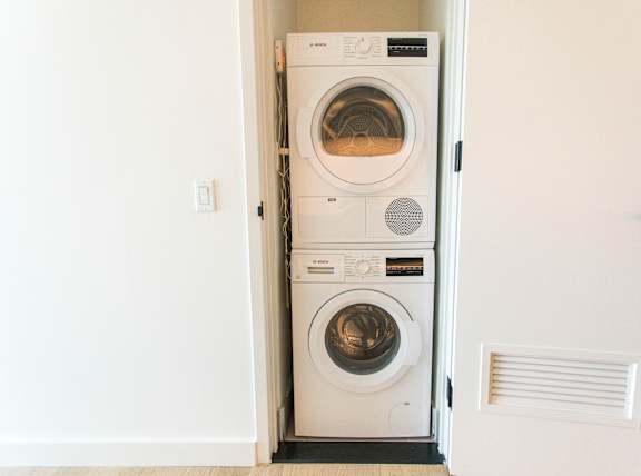 A white door is open to reveal a white dryer and washer.