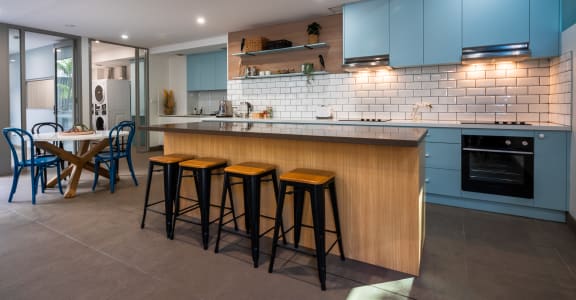 a kitchen with blue cabinets and a bar with stools