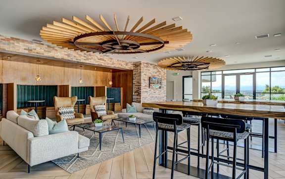 A modern living room with a wooden ceiling fan and a bar area.