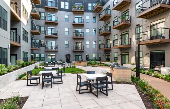 an outdoor patio with tables and chairs in the middle of an apartment building