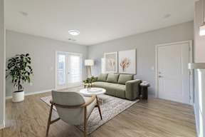 A living room with a green couch, a chair, and a potted plant.