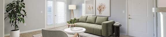 A living room with a green couch, a chair, and a potted plant.