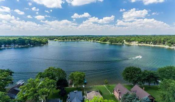 A serene lake surrounded by lush greenery and residential houses.