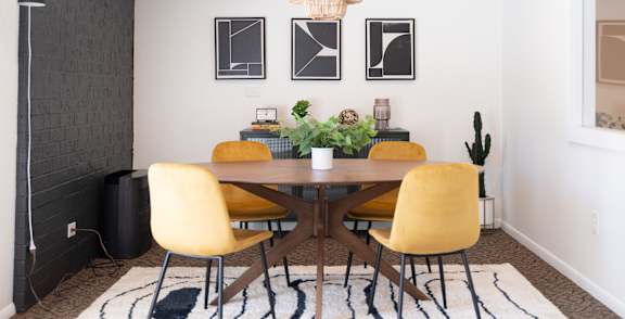 A dining room with a wooden table and yellow chairs.