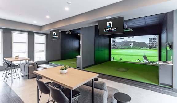 A woman is playing golf indoors with a man watching her.
