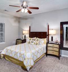 A bedroom with a bed, dresser, and mirror at Austin Chase Apartments, Georgia 31210