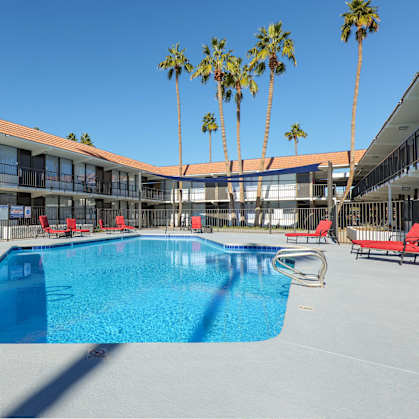 A swimming pool in front of a building with palm trees.