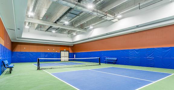 A tennis court with a net and two benches.