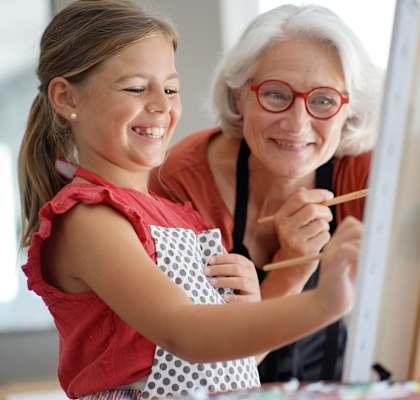 a young girl and an older woman painting on a canvas