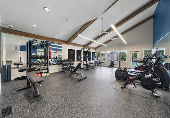 a gym with weights and cardio equipment on the floor and glass walls