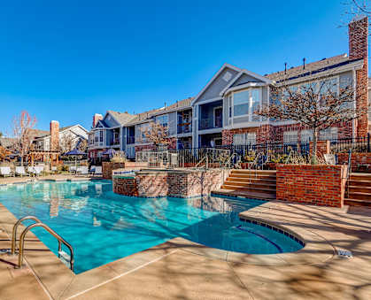 A swimming pool surrounded by a brick wall and steps leading to a building.