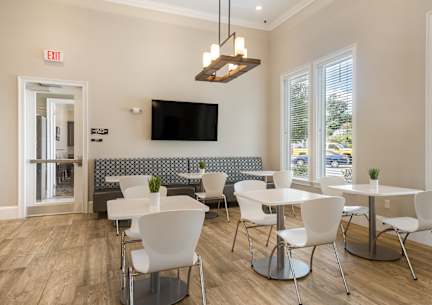 a room with tables and chairs and a tv on the wall