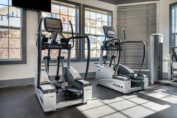 a gym with cardio equipment and windows