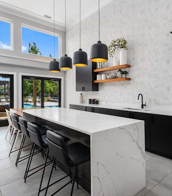 A modern kitchen with a marble island and black cabinets.