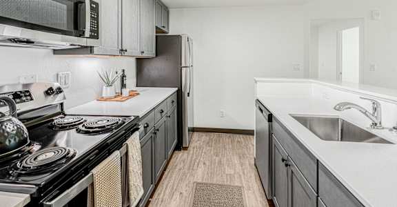 A kitchen with a black stove top oven and a black microwave above it.