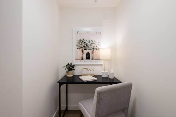 A small table with a chair and a picture on the wall.
