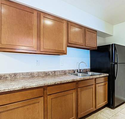 A kitchen with wooden cabinets and a black refrigerator.