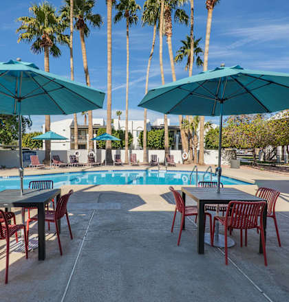 A poolside area with tables and chairs and umbrellas.